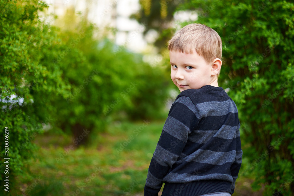 Little boy in a green park looks back. Little boy in a green park looks back.