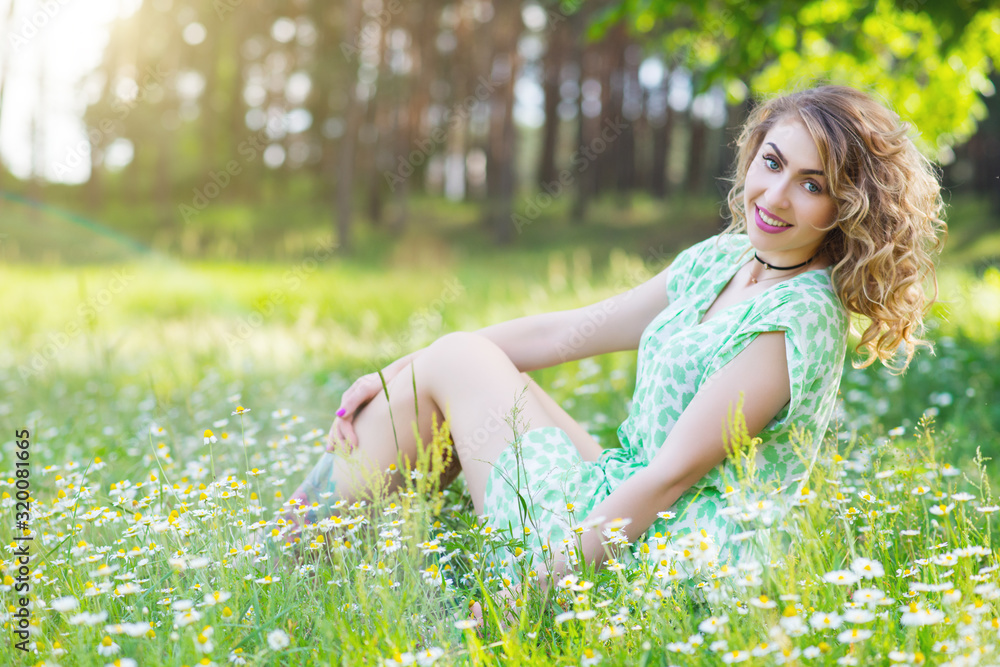 Beautiful feminine young girl sits on the grass Beautiful feminine young girl sits on the grass