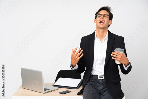 Businessman in his office over isolated white background laughing