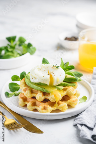 Poached egg with cheese waffles  avocado and corn salad on a white plate. Healthy breakfast. Close-up. Selective focus