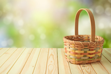 Empty basket on wooden table over green bokeh background. Spring and easter mock up for design.