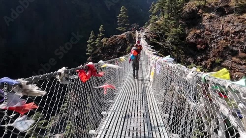 Trekkers and porters crossing a suspension bridge in Everest Region (Sagarmatha National Park - Himalaya), Nepal