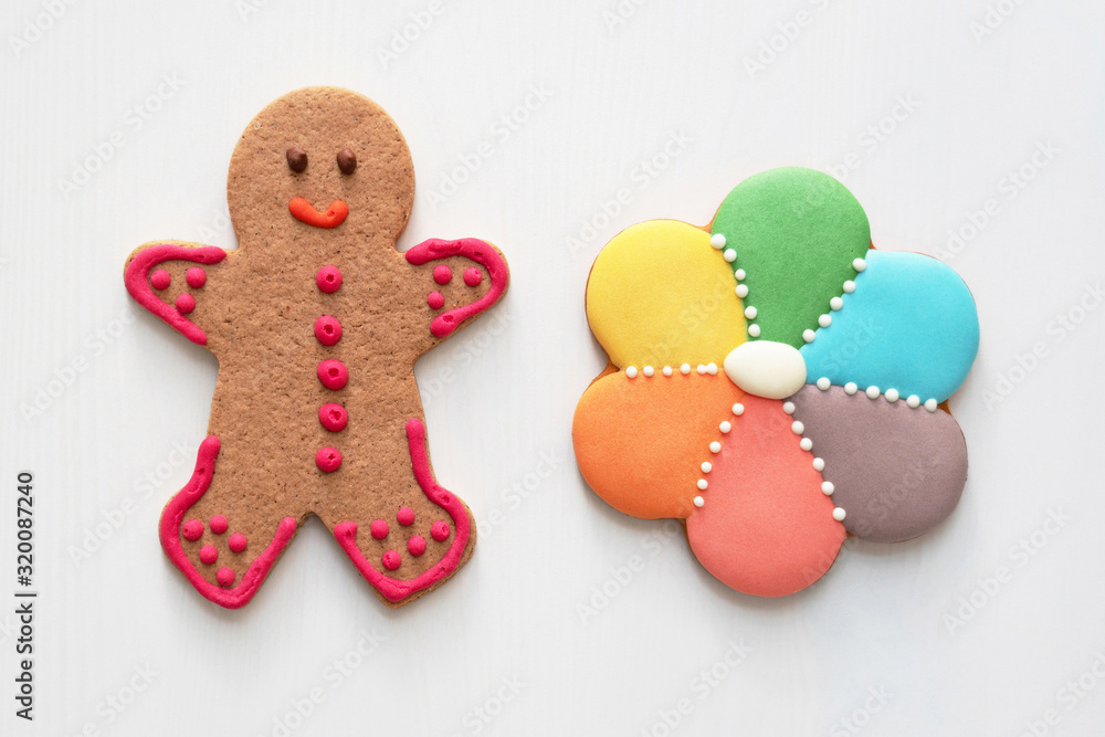 Gingery spice cookies in the form of man and flower with multicolored icing on the white wooden background