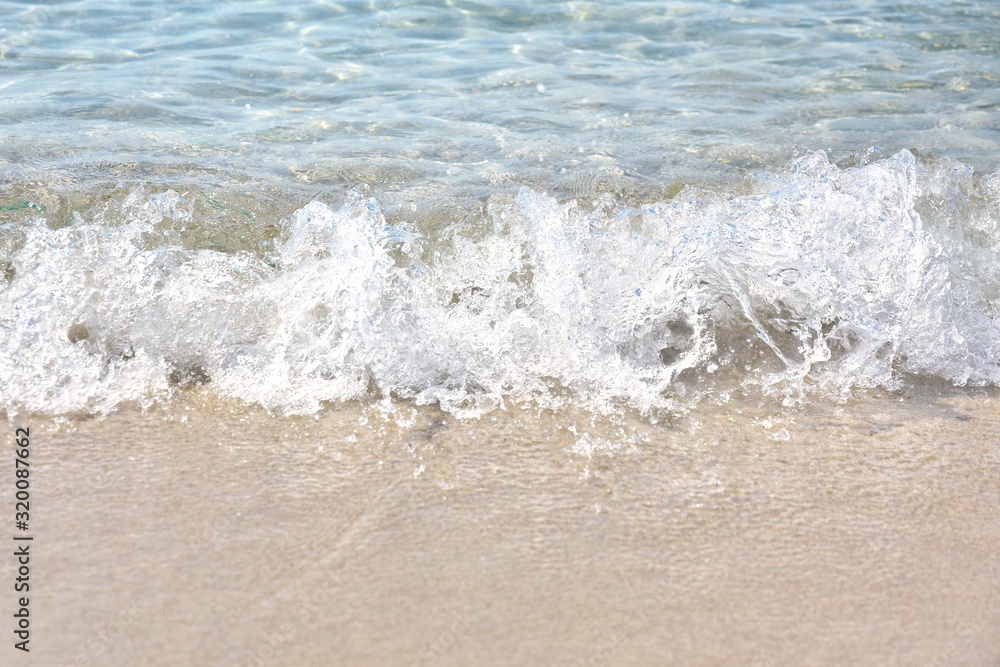 Sea coast with a beautiful soft wave. Transparent blue sea wave with white foam on a clean sandy shore, selective focus. turquoise ocean water. Summertime. Empty sand beach with soft wave background. Sea coast with a beautiful soft wave. Transparent blue sea wave with white foam on a clean sandy shore, selective focus. turquoise ocean water. Summertime. Empty sand beach with soft wave background.