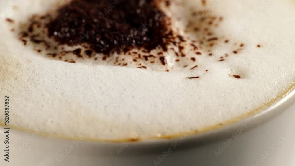 Close up hot coffee cup with milk foam and chocolate decoration on top rotating slowly Close up hot coffee cup with milk foam and chocolate decoration on top rotating slowly