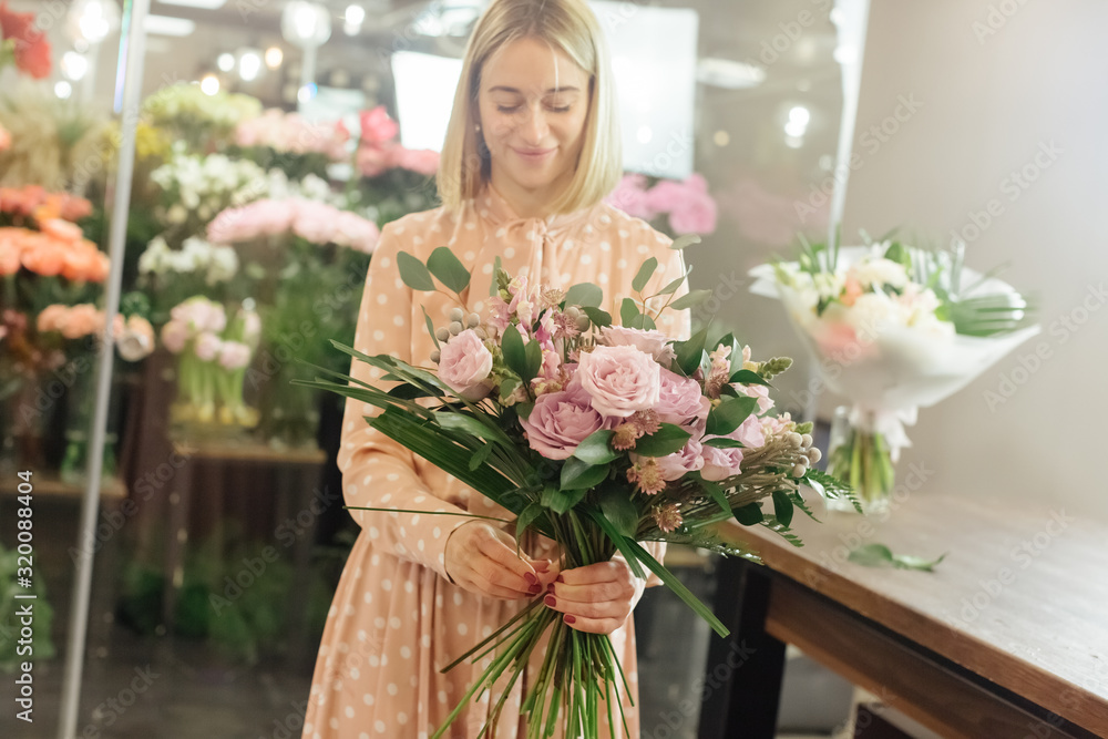 Beautiful smiling female florist in apron arranging bouquet in flower shop Beautiful smiling female florist in apron arranging bouquet in flower shop