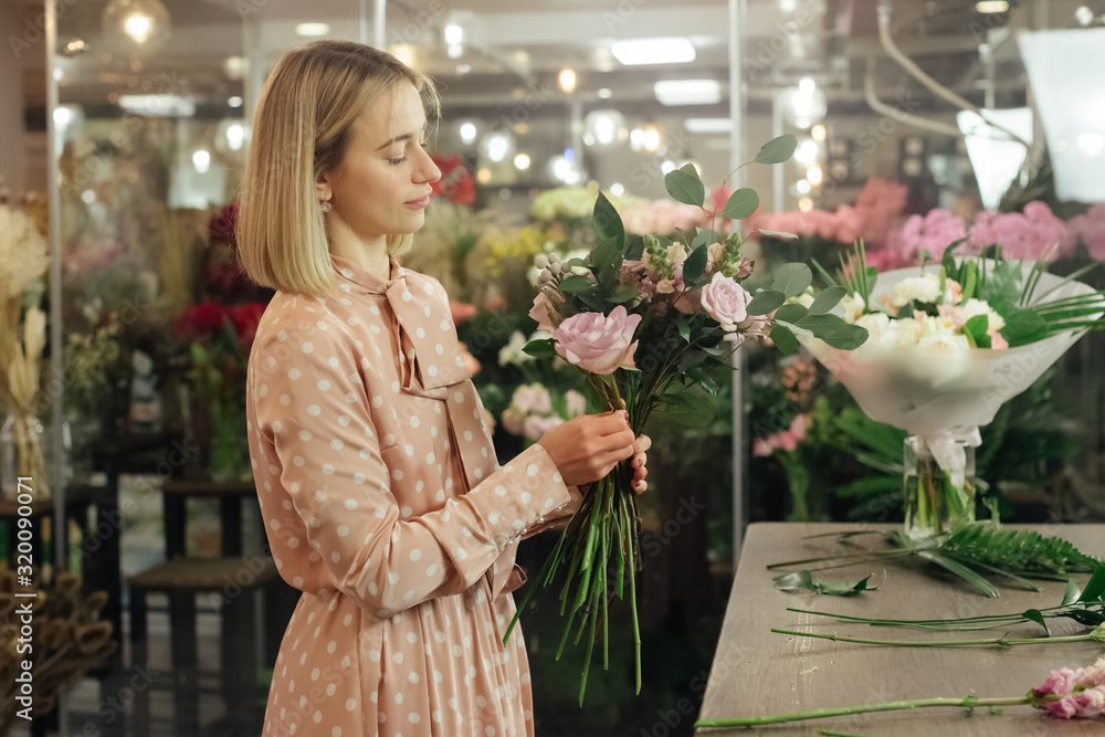 Fototapeta premium Florist makes a bouquet. Working florist in a flower shop. Woman making fashion modern bouquet of different flowers. Women working with flowers in workshop
