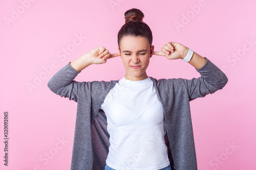 Fényképezés Don't want to listen! Portrait of naughty brunette girl with bun hairstyle in casual clothes covering ears ignoring parental upbringing, disobedient teenager