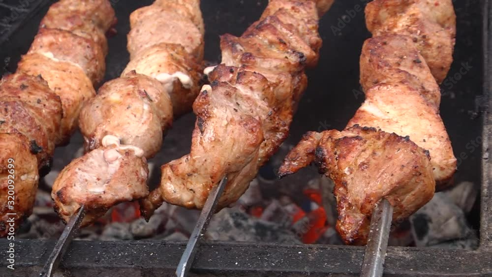 Marinated kebab is cooked on a barbecue grill over charcoal on the street in winter. Grilled pork meat on the barbecue grill. Tasty grilled meat on metal skewers on the brazier in winter. Marinated kebab is cooked on a barbecue grill over charcoal on the street in winter. Grilled pork meat on the barbecue grill. Tasty grilled meat on metal skewers on the brazier in winter.