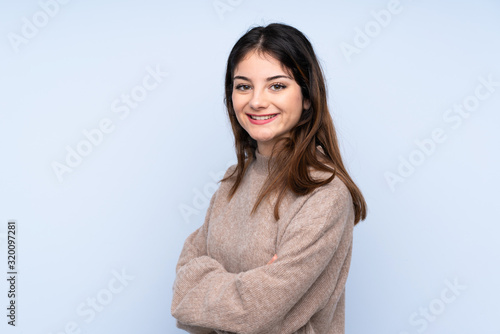 Young brunette woman wearing a sweater over isolated blue background with arms crossed and looking forward © luismolinero