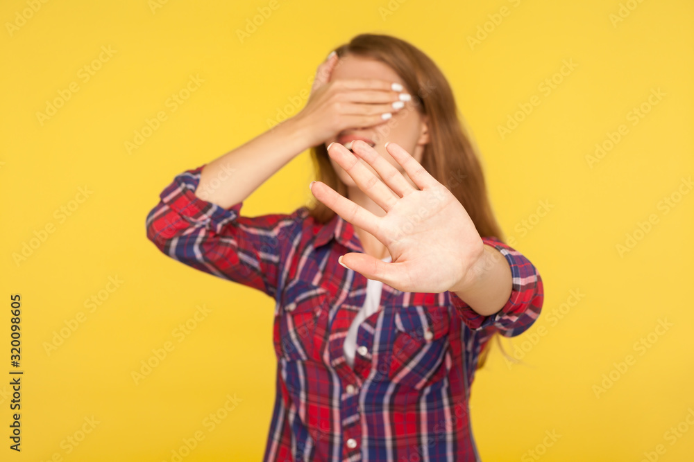 No, I don't want to look. Portrait of girl in shirt covering eyes with hand and showing stop, ban block gesture, being surprised and scared avoiding to watch. studio shot isolated on yellow background No, I don't want to look. Portrait of girl in shirt covering eyes with hand and showing stop, ban block gesture, being surprised and scared avoiding to watch. studio shot isolated on yellow background