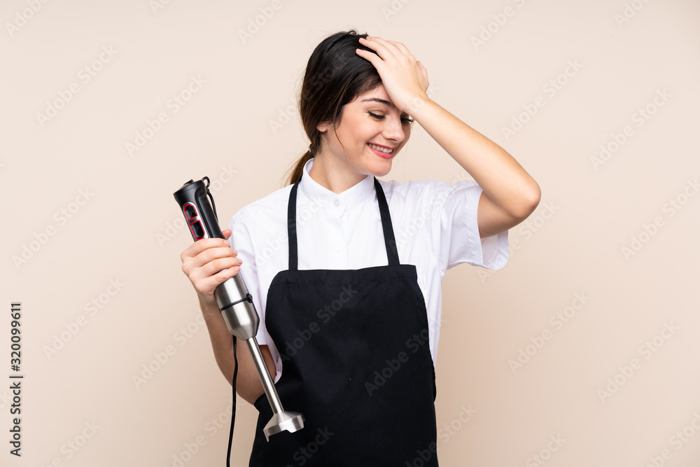 Young woman using hand blender over isolated background has realized something and intending the solution