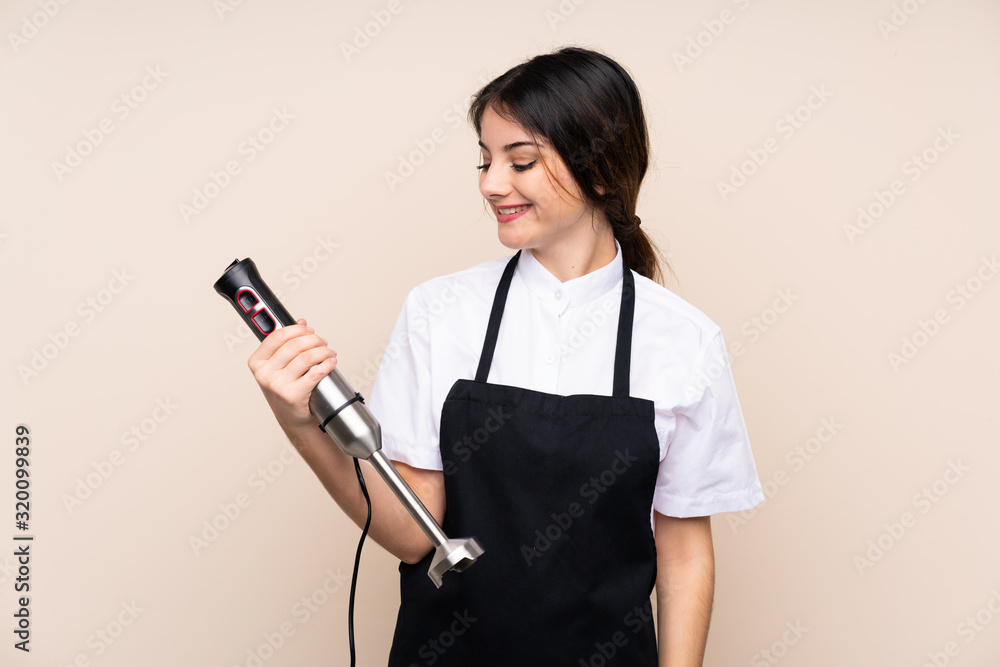 Young woman using hand blender over isolated background with happy expression Young woman using hand blender over isolated background with happy expression