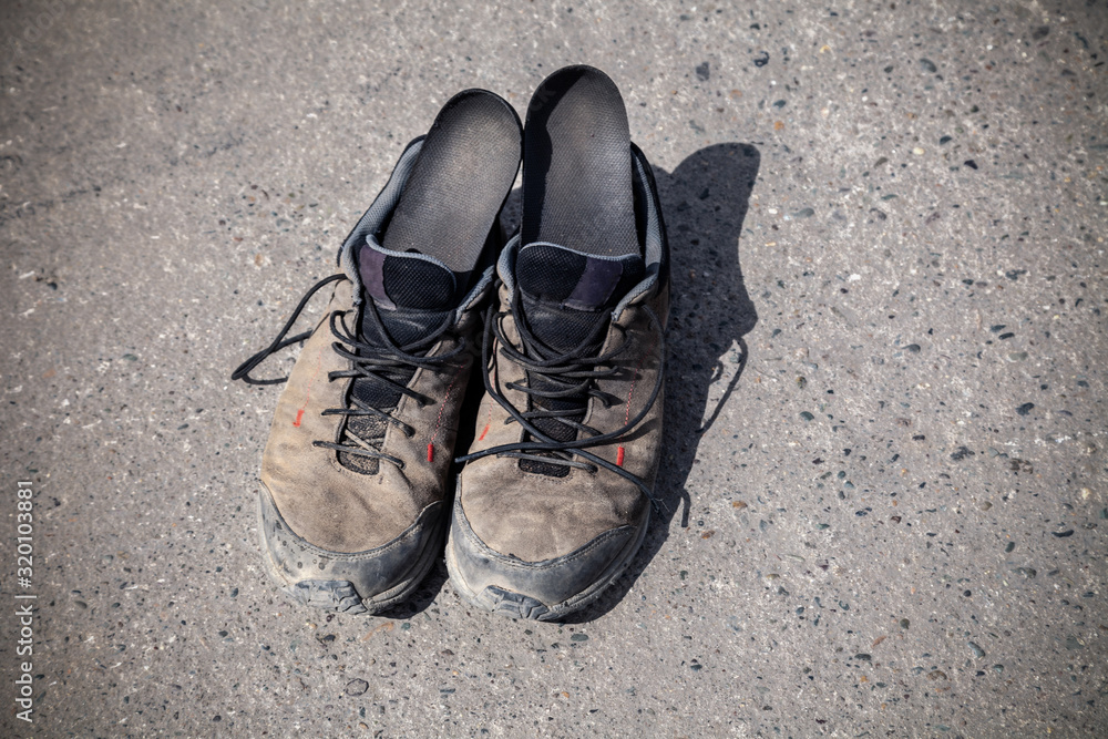 Pair of favorite, worn and dirty high-altitude trekking boots covered in mud and shoelaces, top view. Concept travel, hiking, walking in mountains.