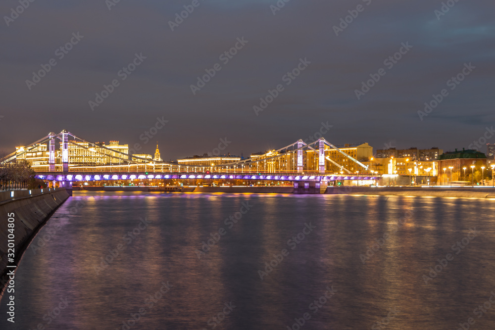Glowing bridge over the river. The far plan. Moscow night