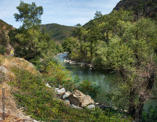 Picturesque Bulgarian landscape with the Struma River in Bulgaria. Winding river surrounded by trees and bushes, sunny summer day