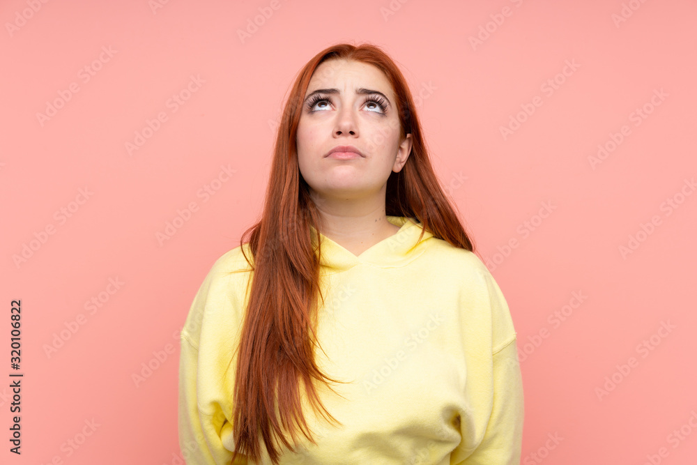 Fototapeta premium Redhead teenager girl over isolated pink background and looking up