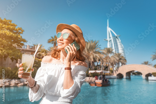 Fototapeta Happy girl drinking mojito cocktail in Dubai resort
