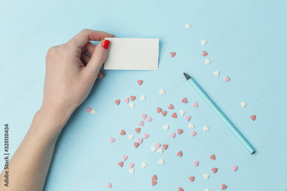 Top view of female writing a note on blue background, Valentine's day, Mother's day, holiday concept