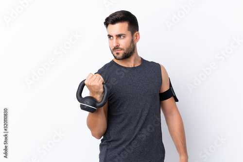Young sport handsome man with beard over isolated white background making weightlifting with kettlebell