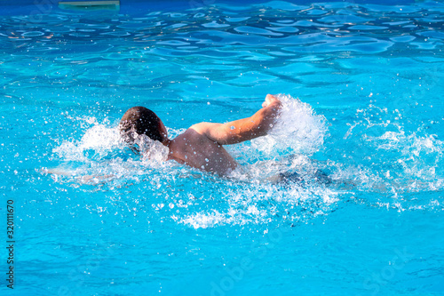 Young guy swims in the pool. Vacation at the resort_