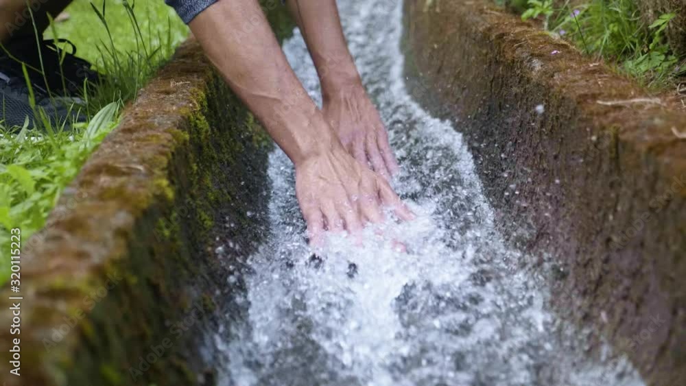 A man enjoying the feel of the cool, refreshing water with his hands in Madeira, Portugal - Slow motion A man enjoying the feel of the cool, refreshing water with his hands in Madeira, Portugal - Slow motion