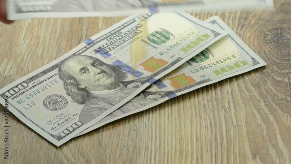 Counting new hundred US dollar notes on a table. Counting new hundred US dollar notes on a table.