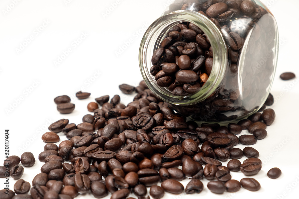 Fototapeta premium Scattered coffee beans from a transparent jar on a white background