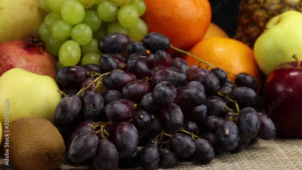 A large pile of different fruits lies on a gray surface, close-up A large pile of different fruits lies on a gray surface, close-up