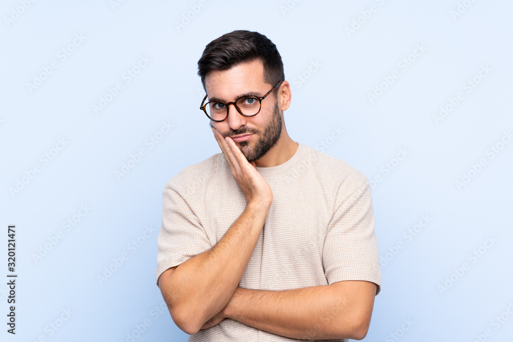 Young handsome man with beard over isolated blue background unhappy and frustrated