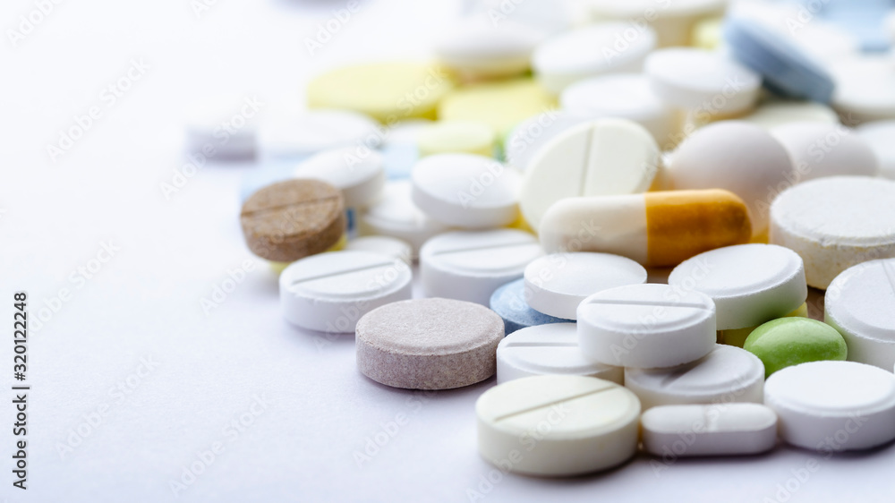 bright pills of different shapes and colors close-up on a white background, soft focus bright pills of different shapes and colors close-up on a white background, soft focus