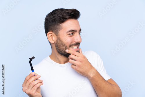 Young handsome man shaving his beard over isolated background thinking an idea and looking side