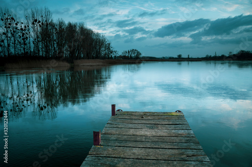 Cloudy and cold winter evening, freezing lake with a pier