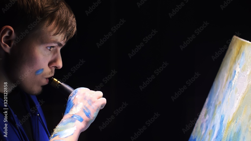 Fototapeta premium Artist copyist paint seascape with ship in ocean. Vaper smoke vape e-cigarette. Craftsman decorator draw as boat sail on blue sea with acrylic oil color. Draw finger, brush, knife palette. Indoor.