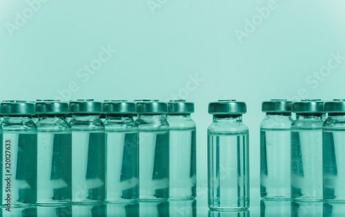 Glass medical ampoule vial for injection. Medicine is liquid sodium chloride with of aqueous solution in ampulla. Close up. Bottles ampule multicolor on background color and water. Human plasma. photo