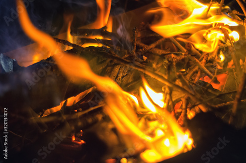 Burning firewood at night. Flames and fire sparks on a dark abstract background.