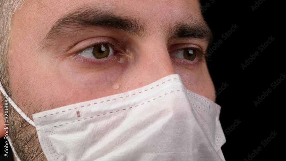 A man in a medical mask crying