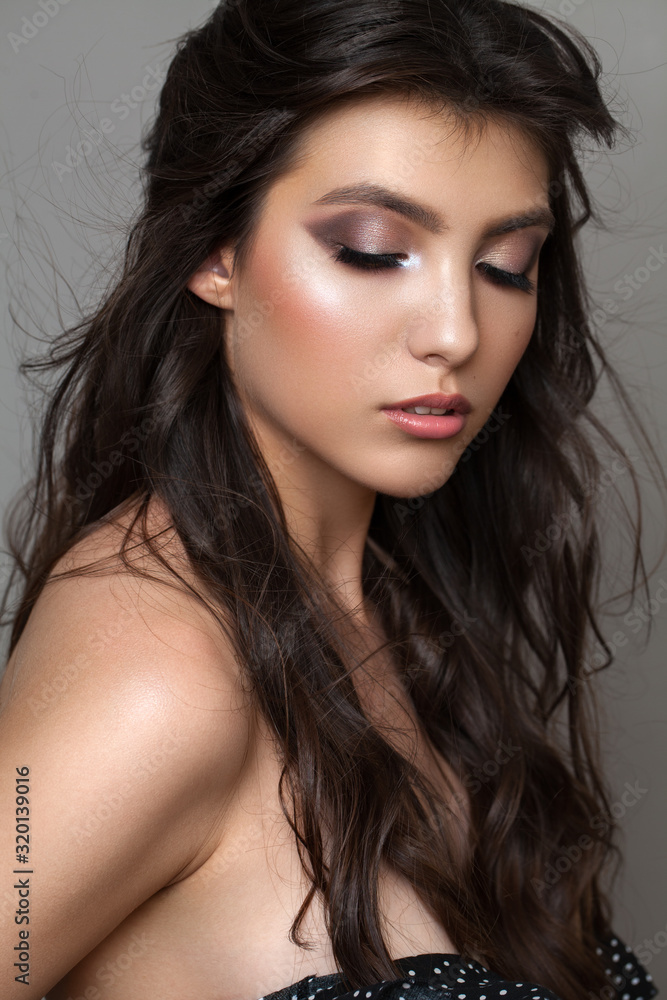 Photo of a very beautiful young girl with closed eyes, professional makeup, perfect skin and rich natural hair.