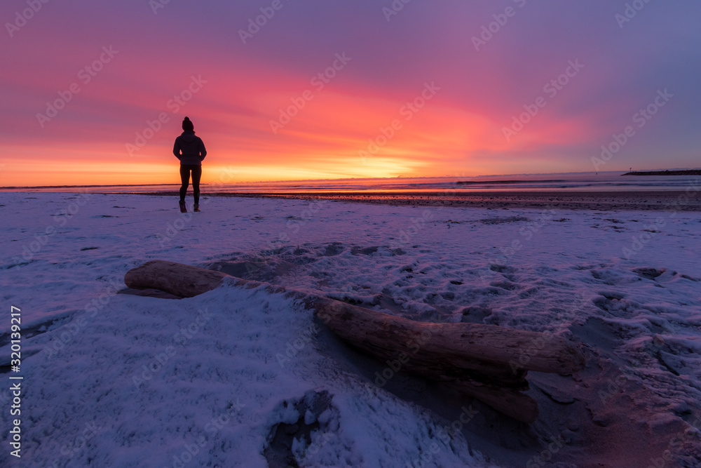 Winter sunrise on Drakes Island Beach, Maine with person silhouette.