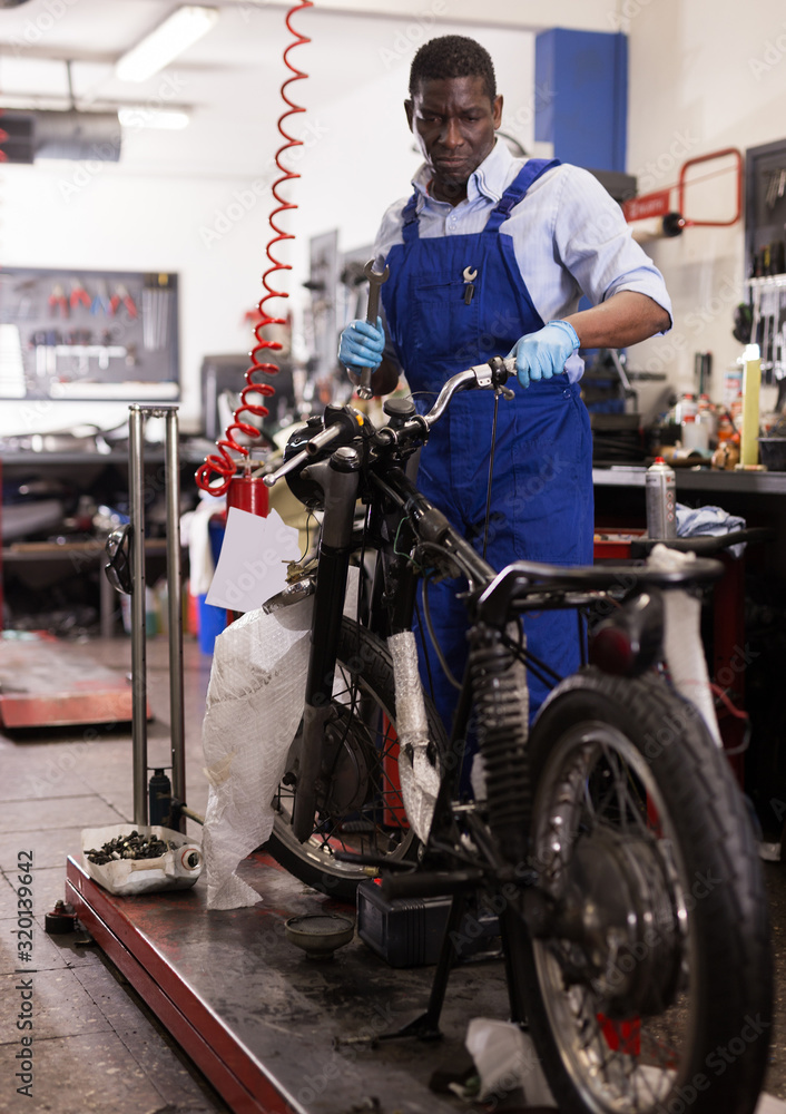Service engineer repairs a motorcycle steering wheel in a motorcycle service