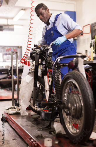 Service engineer repairs a motorcycle steering wheel in a motorcycle service