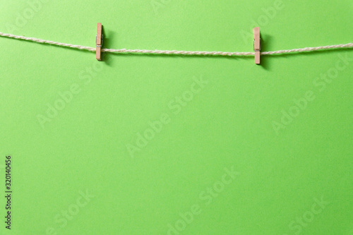 An empty template with a rope and tiny clothespins on a green background.