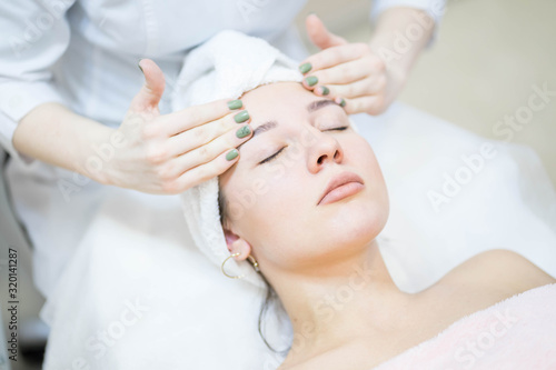 Woman in white and pink towel is having a face massage from a doctor cosmetologist in a white  uniform © Nanabrooks