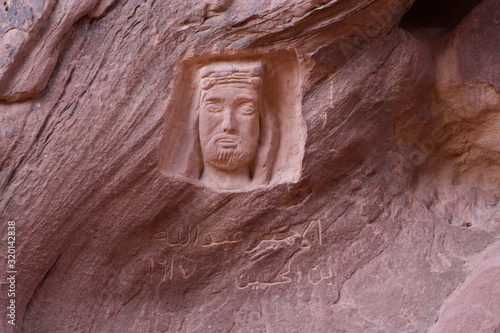 Old portrait of Lawrence of Arabia is carved in red sandstone rock in canyon Siq Um Al Tawaqi in Barrah Gorge in Wadi Rum desert in Jordan. photo