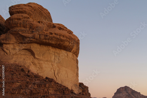 Textured sandstone mountain in Wadi Rum desert in Jordan after sunset. Beautiful landscape. Theme of travel and safari in Jordan.