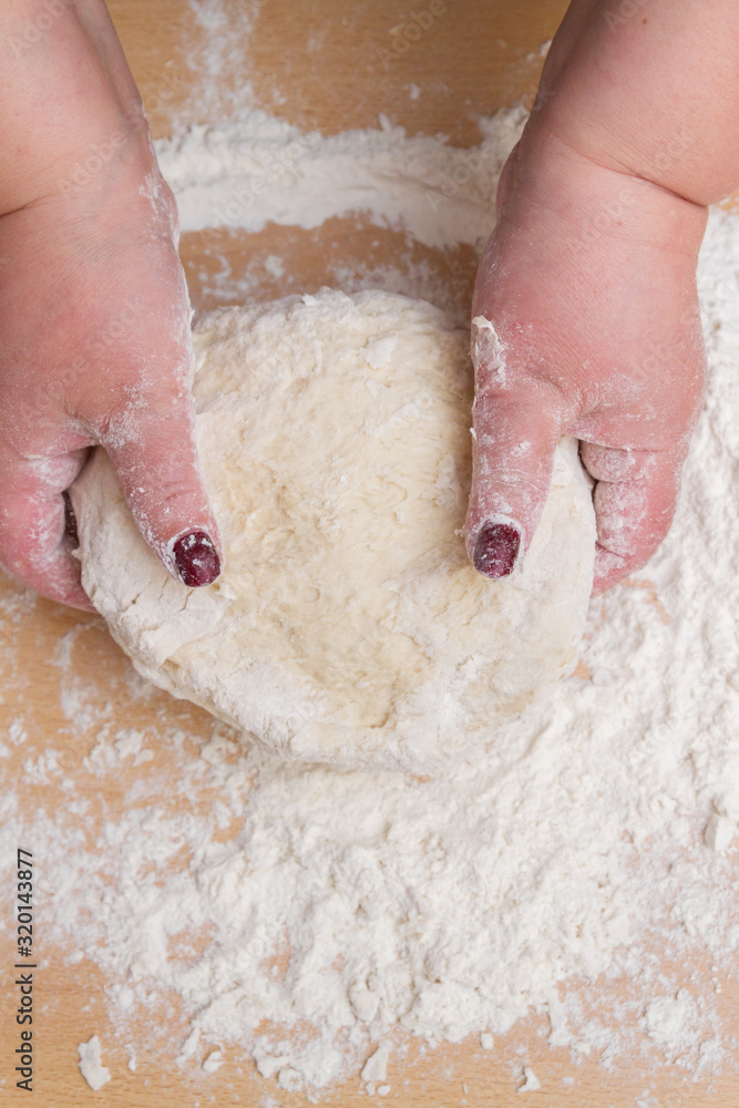 Kneading dough with flour on a wooden table at home Kneading dough with flour on a wooden table at home