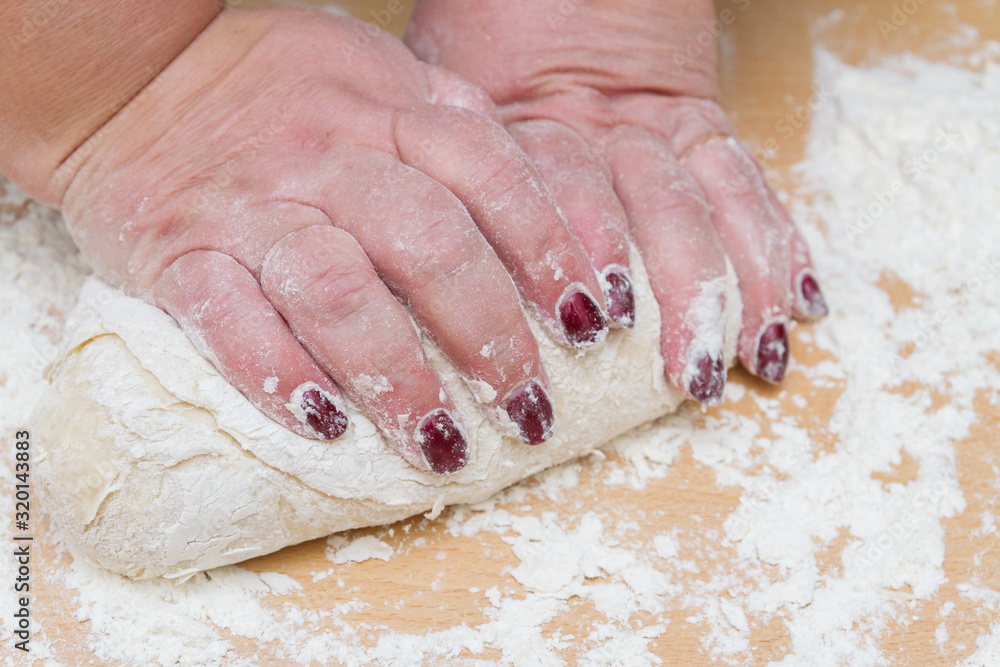 Kneading dough with flour on a wooden table at home