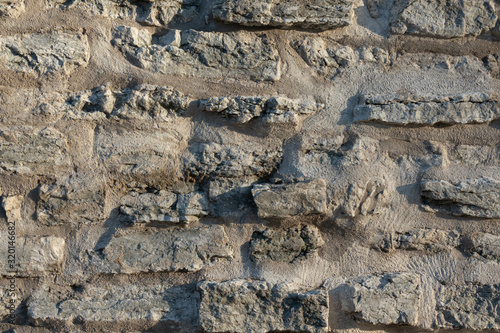 Fragment of a satar wall of gray flat stones. The masonry is connected by a gray cement composition. Background. Texture. photo