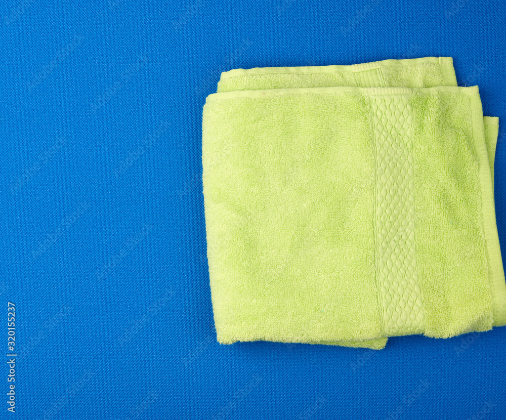 Fototapeta premium folded bath terry light green towel on a blue background