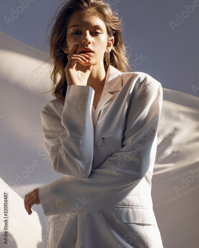  Girl in a white jacket on the background of a flying veil and blue sky
